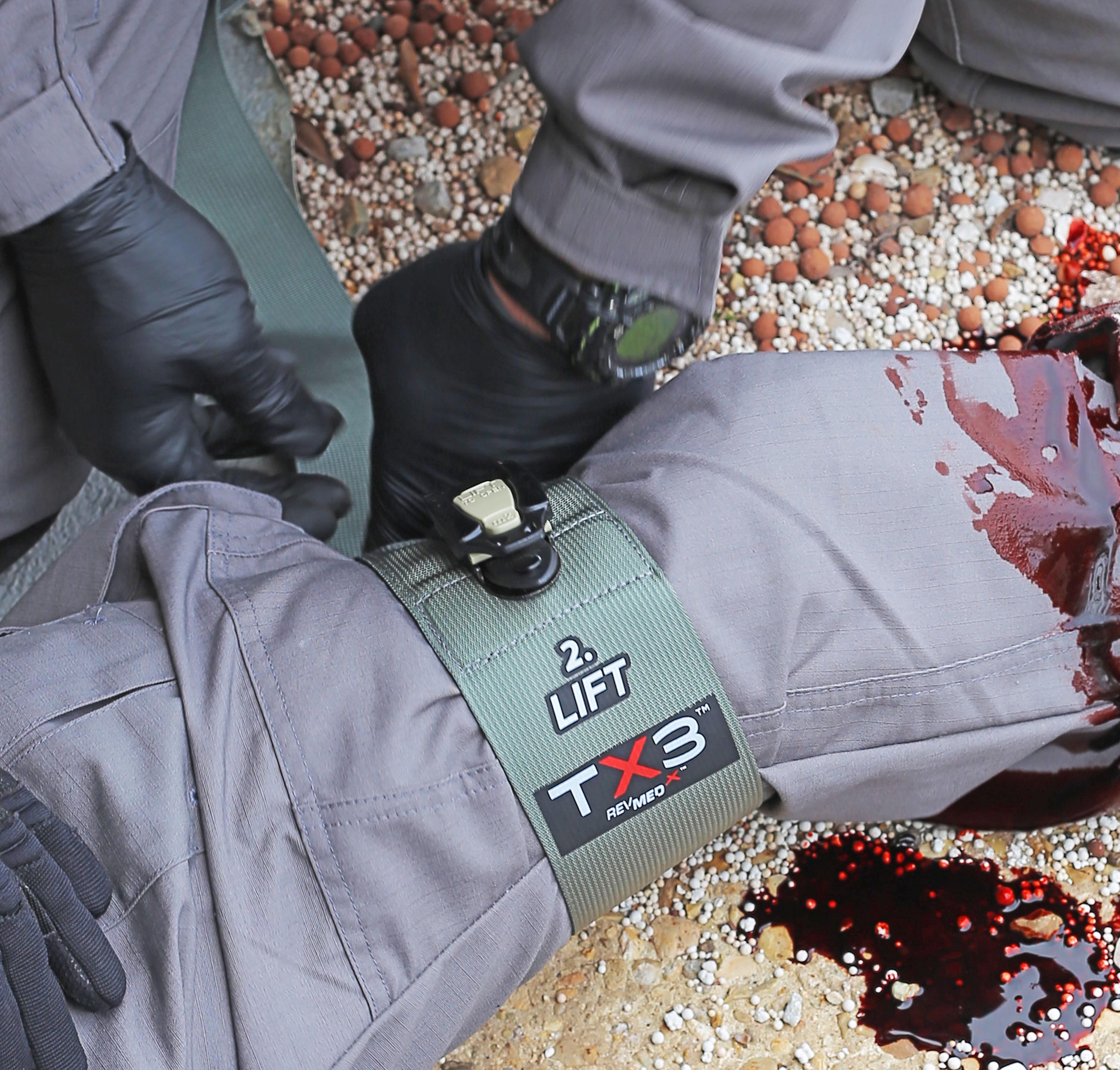 TX3 ratcheting tourniquet applied to leg, showing wide 3-inch band securing limb with advanced ratcheting mechanism